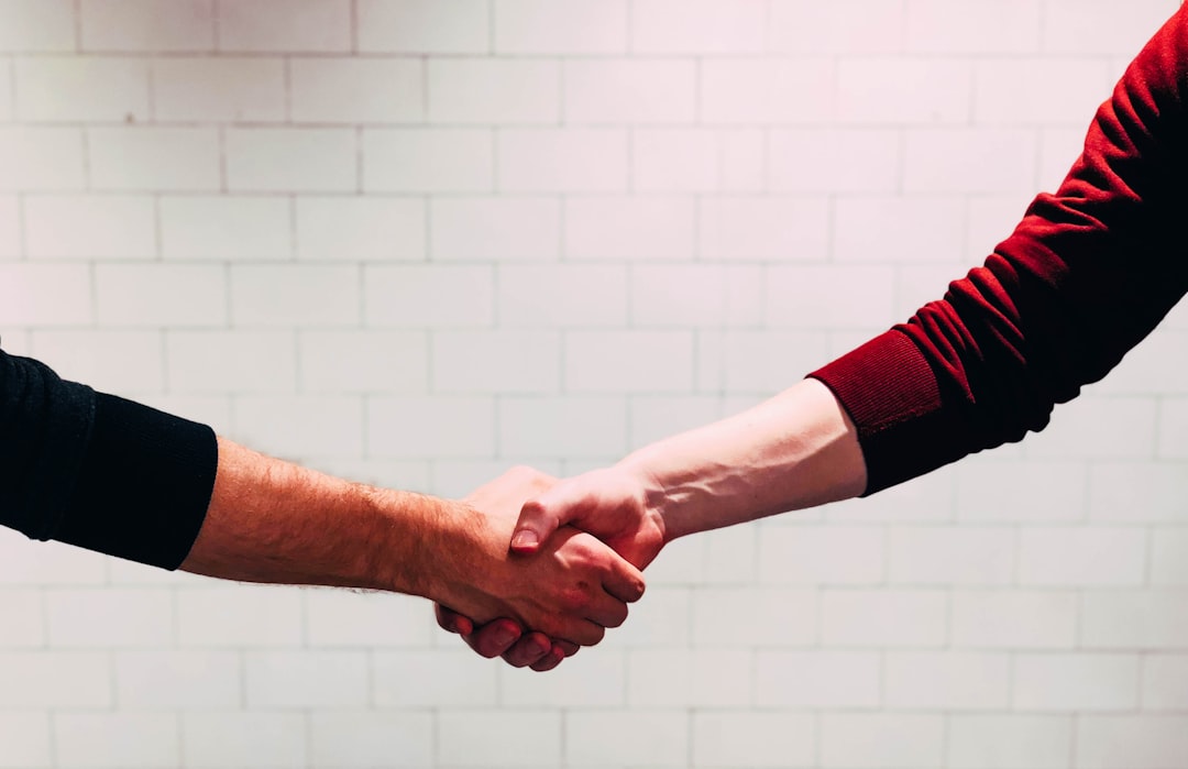 two-person-shaking-hands-near-white-painted-wall-9cd8qogeniy Handshake